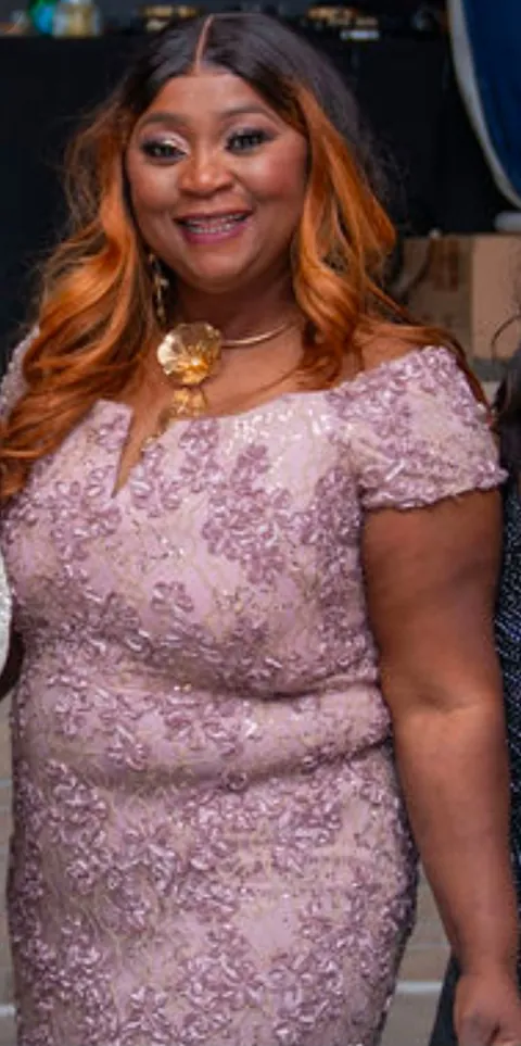 Memuna smiling in a pink lace dress