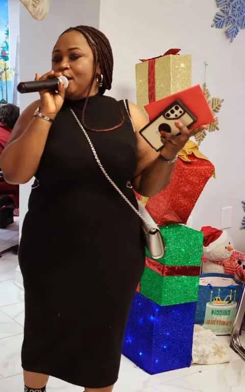 Memuna singing with a microphone beside wrapped gifts