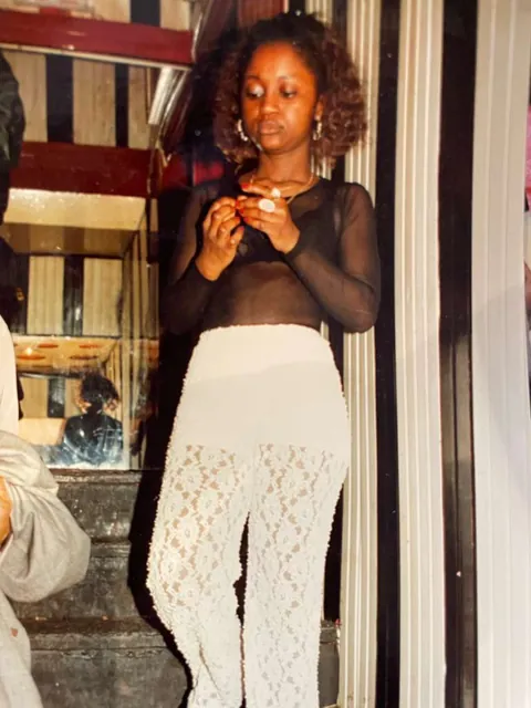 Memuna in a sheer top and white lace pants