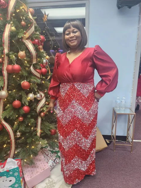 Memuna by the Christmas tree in a red sequined gown